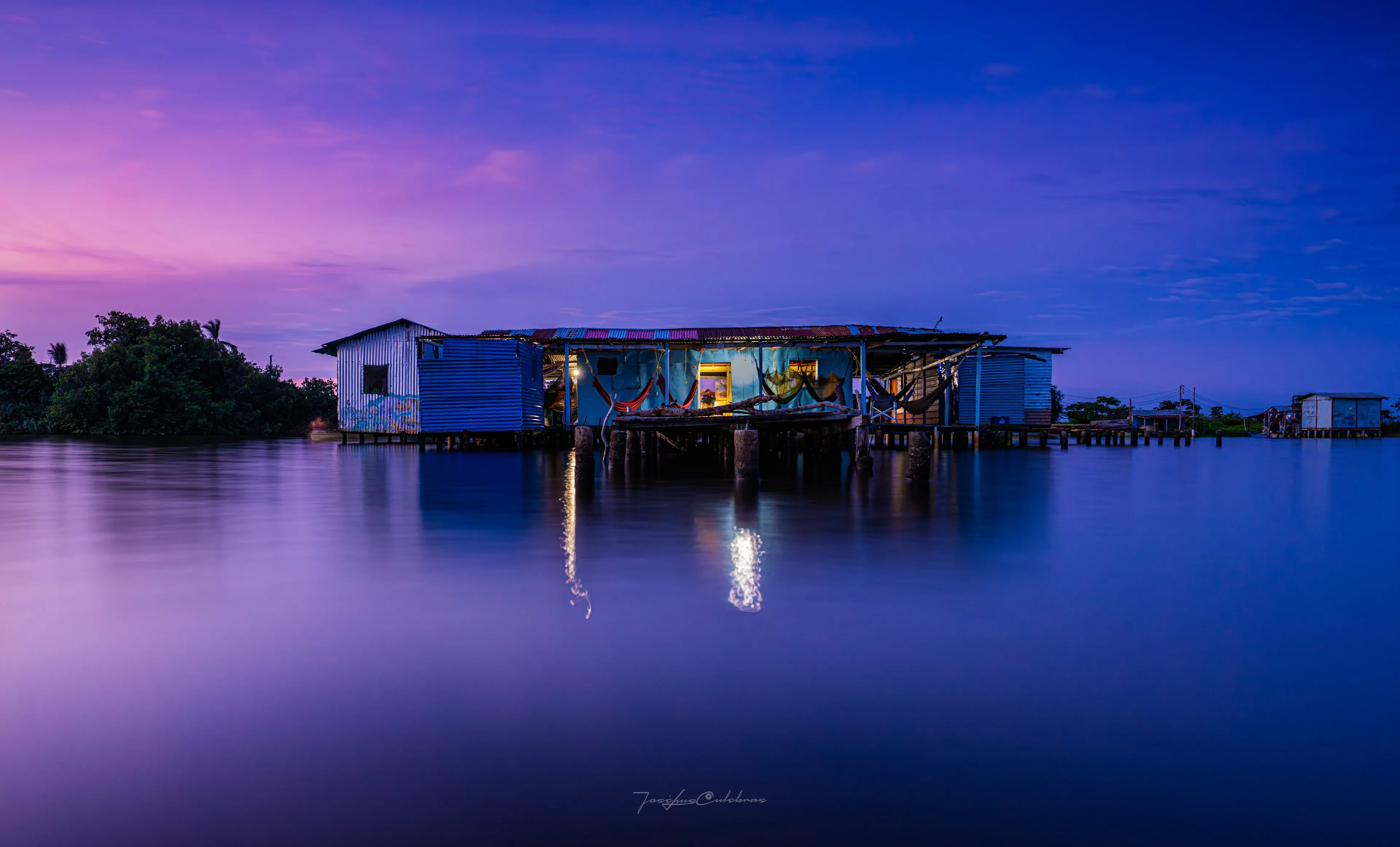 Ologá — palafito iluminado sobre el lago al atardecer